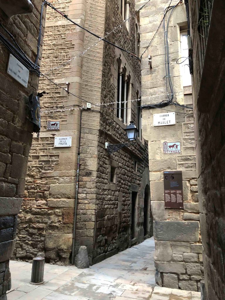 View of Barcelona's narrow Gothic Quarter streets and old entry and exit signs