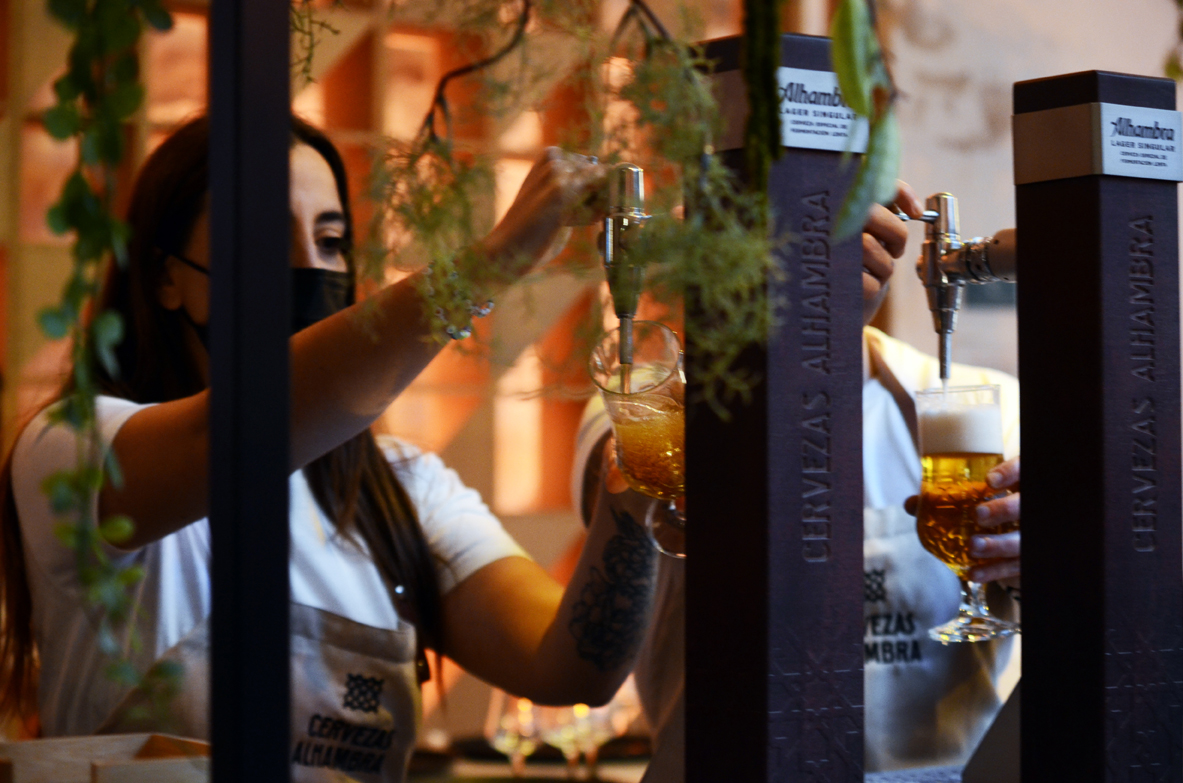 Woman bartender serving Cervezas Alhambra beer from tap
