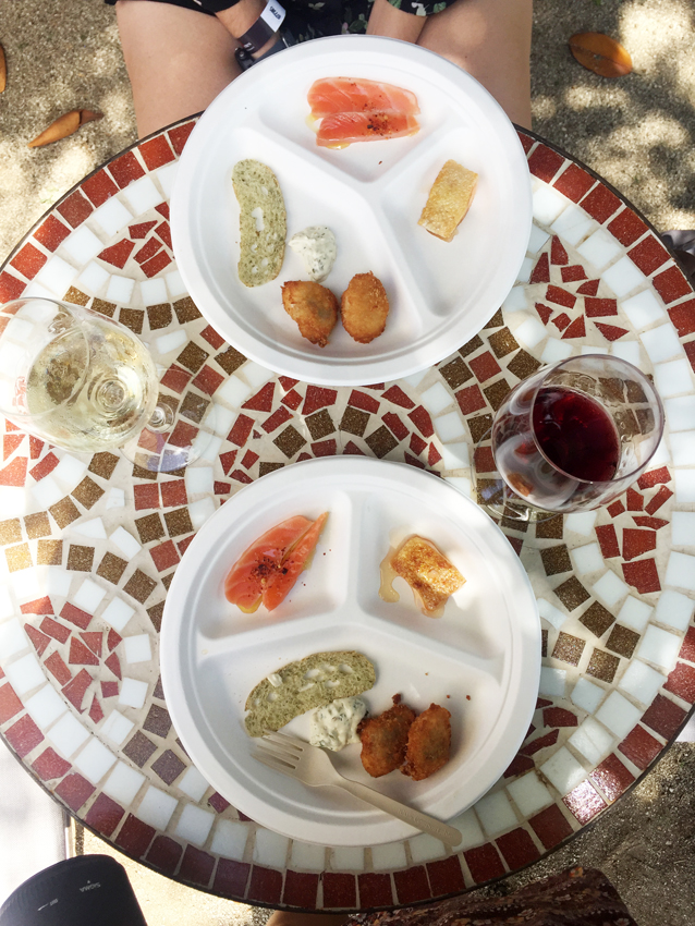 Aerial view of two plates with salmon preparations on a tiled table between glasses of wine