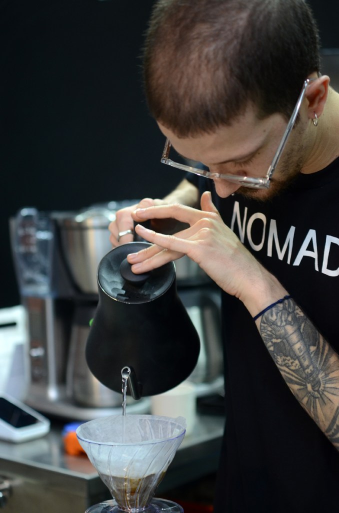 Barista concentrating on pouring water into V60 coffee machine